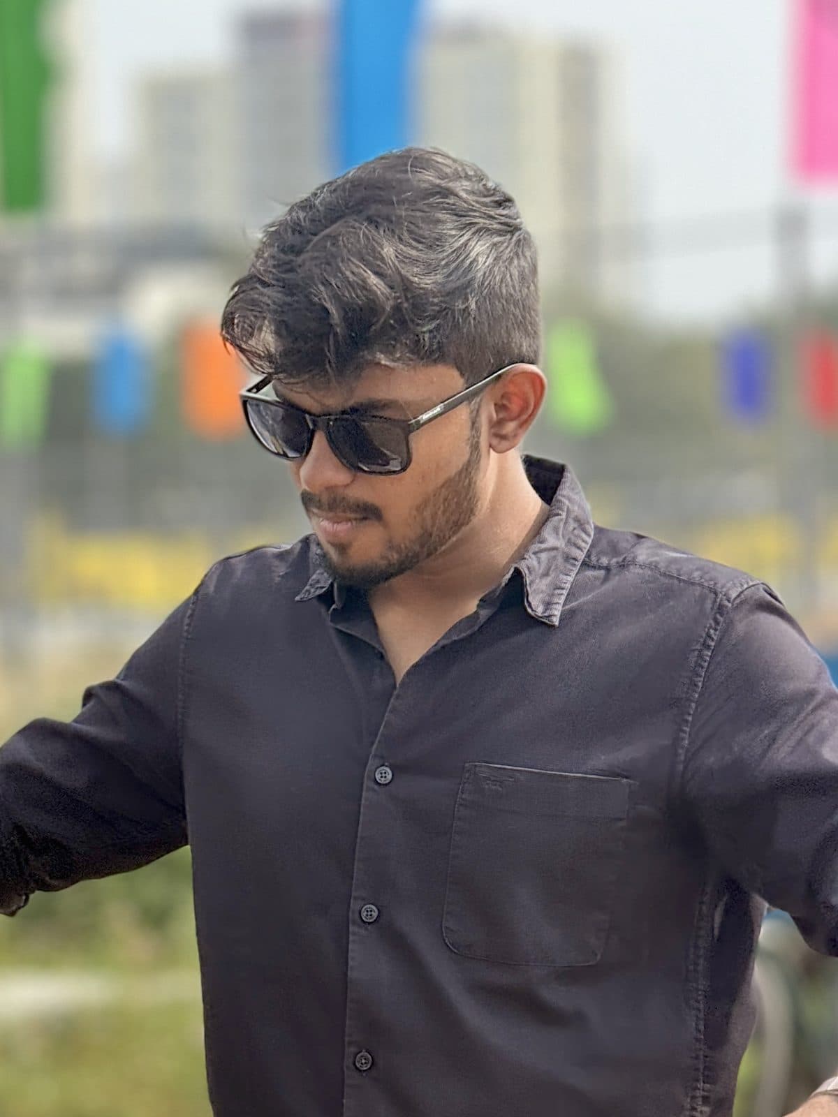 Bharath Kumar A A, wearing sunglasses and a dark shirt, looking down to the side